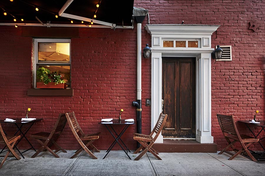 Business Insurance - Exterior Shot of a Small Restaurant With a Red Brick Wall and Wooden Door