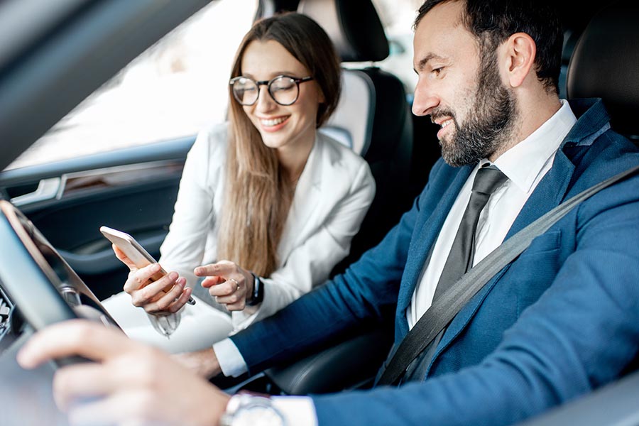 Client Center - Two Businesspeople Using a Phone in a Car, Wearing Suits